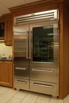 a stainless steel double door refrigerator in a kitchen with wooden cabinets and tile flooring