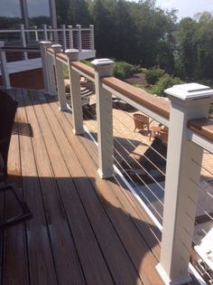 an image of a wooden deck with white railings and chairs on the other side