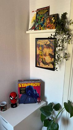 there is a spiderman poster on the wall next to a toy and some plants