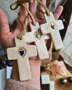 a person holding four wooden crosses with hearts on them