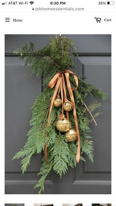 a christmas wreath with bells hanging from it's side on the front door,