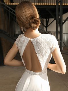 the back of a woman's white dress with an open neck and lace detailing