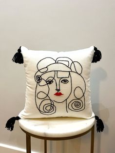 a white pillow with black tassels and a woman's face on it