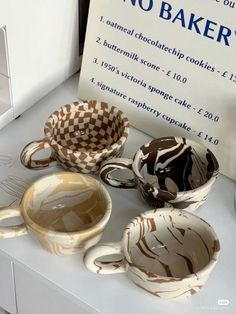 three coffee cups sitting on top of a counter next to a no bake sign