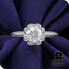 a white gold ring with an old cut diamond surrounded by pave diamonds on a purple satin background