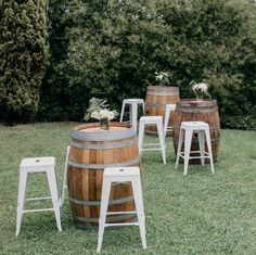 wooden barrels and stools are set up in the grass for an outdoor wedding ceremony