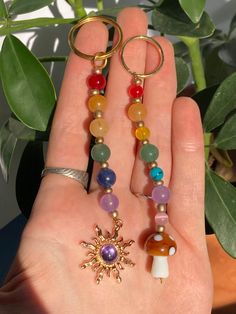 a person is holding some colorful beads in their hand with a sun charm on it