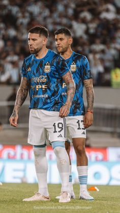 two soccer players standing next to each other on a field