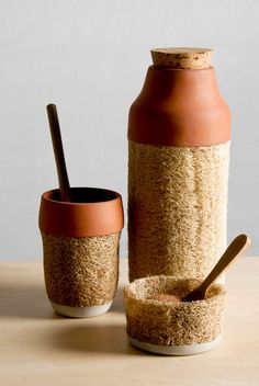 a brown and white vase sitting next to a cup on top of a table