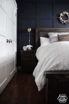 a bedroom with dark blue walls and white bedding