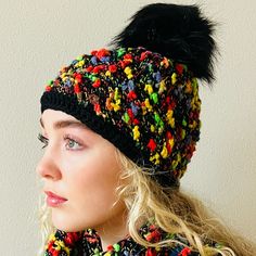 a woman wearing a multicolored knit hat with black pom - pom