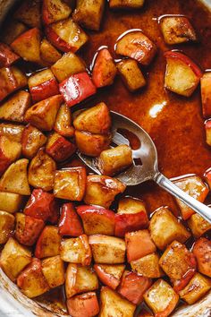 a pot full of cooked potatoes and sauce with a spoon in it on the side