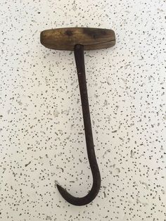 an old hook with a wooden handle hanging from it's side on a white wall