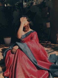 a woman in a red and black dress sitting on the ground with her eyes closed