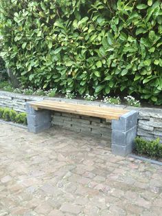 a wooden bench sitting next to a stone wall