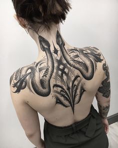 the back of a woman's body with tattoos on it