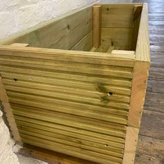 a wooden box sitting on top of a wooden floor next to a white brick wall