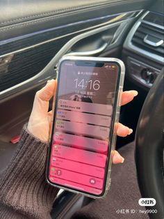 a person holding up a cell phone in their hand while sitting in the driver's seat of a car