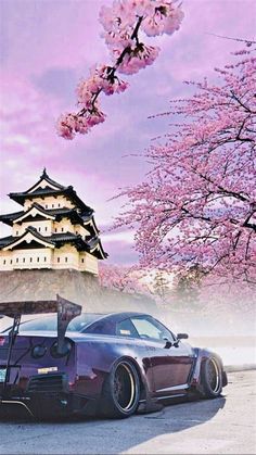 a car parked in front of a tall building with cherry blossoms on it's trees