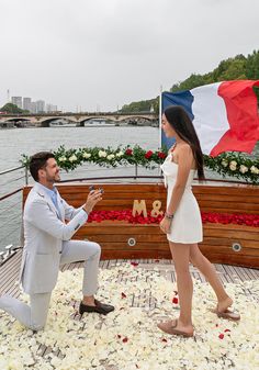 a man kneeling down next to a woman on a boat with flowers all over it