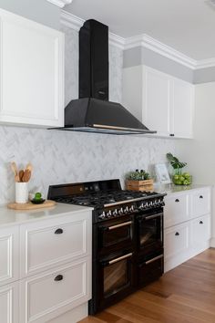 a stove top oven sitting inside of a kitchen next to white cupboards and drawers