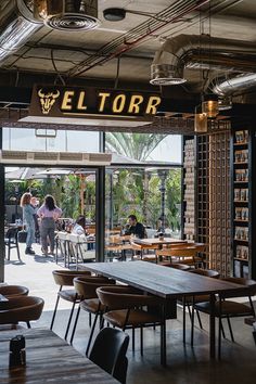 the interior of a restaurant with people sitting at tables and looking out to the outside