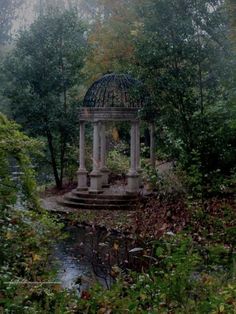 a gazebo surrounded by trees and water in the middle of a wooded area with lots of greenery