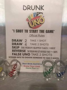 some glasses are sitting on a table next to a sign that says drunk uno, shot to start the game