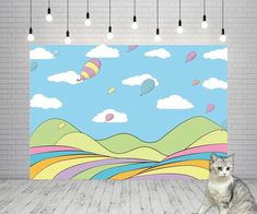 a cat is sitting on the floor in front of a wall with an image of hot air balloons