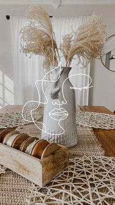 a vase filled with flowers sitting on top of a wooden table next to rolls of tape