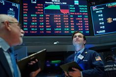 two men standing in front of an electronic stock board