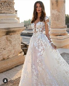 a woman in a wedding dress standing near columns