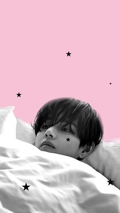 a young man laying in bed with stars on the sheets and pink sky behind him