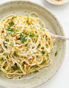 a plate of spaghetti with parmesan cheese and herbs on the side, ready to be eaten