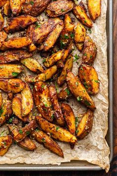 baked potato wedges on parchment paper with parsley sprinkled around the edges