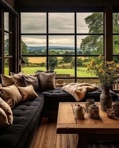 a living room filled with lots of furniture next to a large window covered in windows