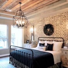 a bedroom with brick walls and wood floors, white bedding, chandelier