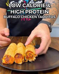 a person is grabbing some food from a plate on a table with the words low calorie and high protein buffalo chicken taquitos