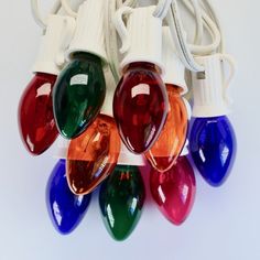 multicolored christmas lights are hanging on a white cord and plugged into cords