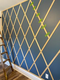 a ladder is next to a wall painted with blue and green geometric designs on it