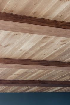 the underside of a wooden structure with wood slats on it's sides and blue sky in the background