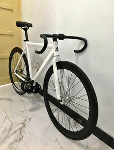 a white and black bike leaning against a wall