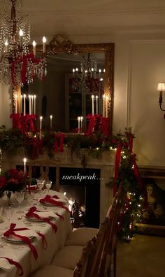 a dining room table set for christmas dinner with candles and red ribbon on the table