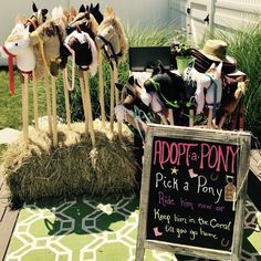 several horse heads are placed on top of hay in front of a sign that says adopt a pony pick a pony