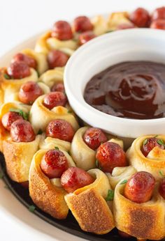 a platter filled with pigs in a blanket and dipping sauce