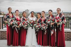 a group of women standing next to each other on top of a roof holding bouquets