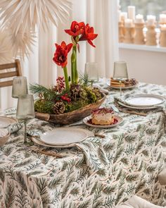 a table topped with plates and flowers on top of a cloth covered dining room table