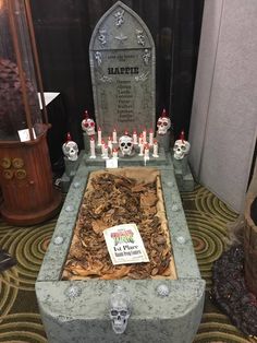 a grave with candles and skulls on it in a room filled with other items,