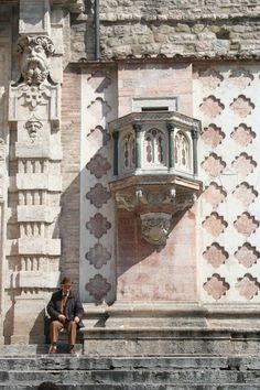 a man sitting on some steps next to a building with a water fountain in front of it