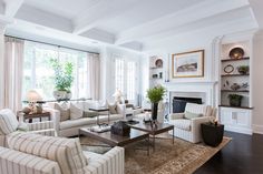 a living room filled with furniture and a fire place in front of a large window